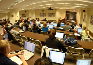 Law students sit with open laptops, listening to their professor give a lecture.