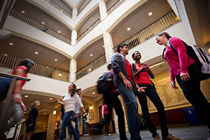 Angled, upward view of diverse students chatting in an atrium.