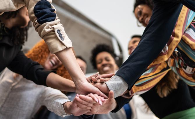 Group of diverse individuals in a huddle with hands overlapped