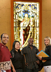 Group photo of students standing in front of stained-glass window