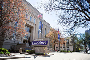 Angled view of the Law School exterior. An American flag flies in front of the main entrance. Many deciduous trees are in view; some are bare, some covered in orange leaves.