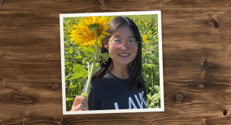 Bingran Li holding sunflower in field of sunflowers.