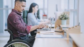 Student in wheelchair using laptop at testing center