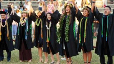 Group of students in graduation gowns cheering