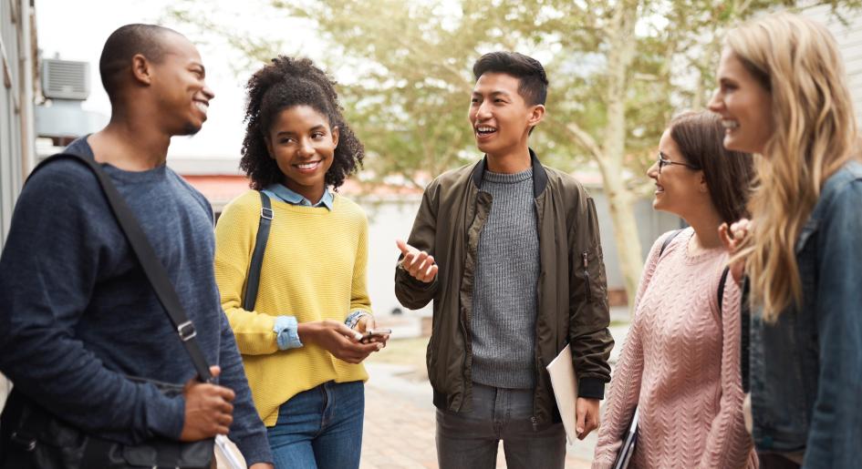 A group of students stand in a semi-circle and talk to each other