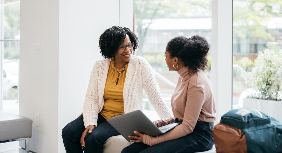 Law student with laptop conversing with professor/mentor.