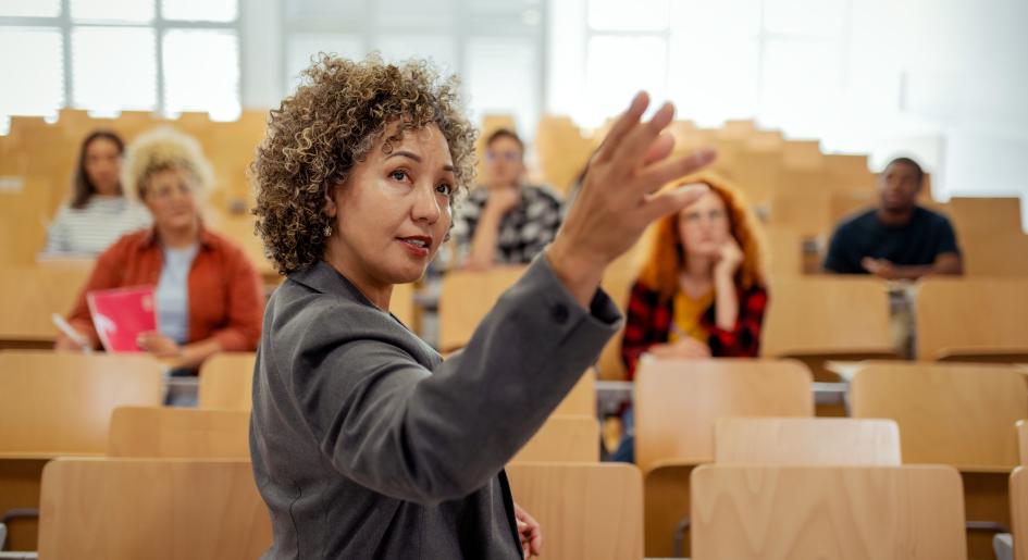 A woman gestures with her hand while teaching a class