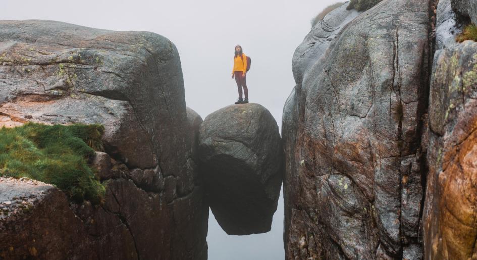 Person standing on rock held between two precipices