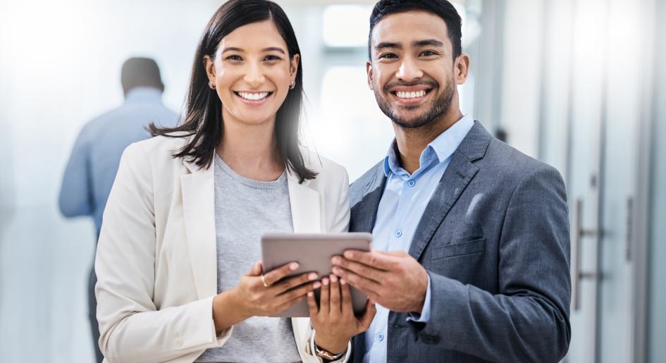 Two Hispanic people holding tablet and smiling.