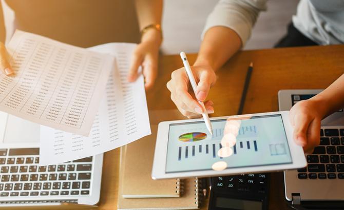 researchers study paperwork and examine charts and figures on a tablet