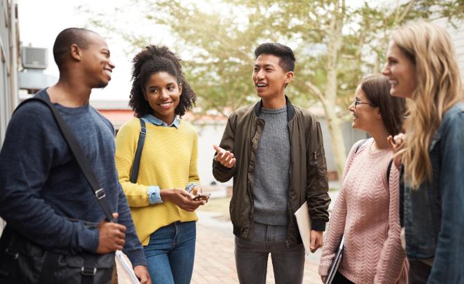 A group of students stand in a semi-circle and talk to each other