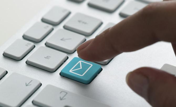 A hand selects a button from a keyboard with a mail icon on it