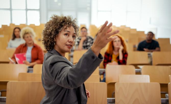 A woman gestures with her hand while teaching a class